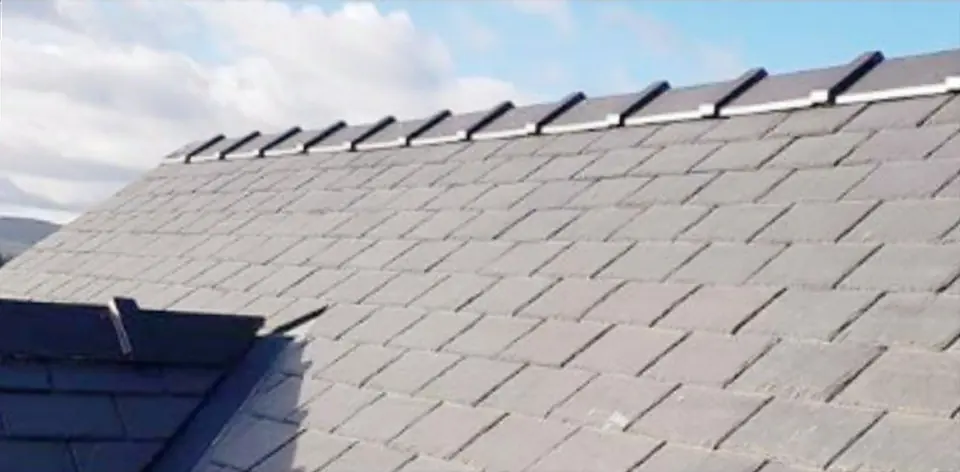 Rows of grey slate running up to the ridge, with a second slate roof at the lower left