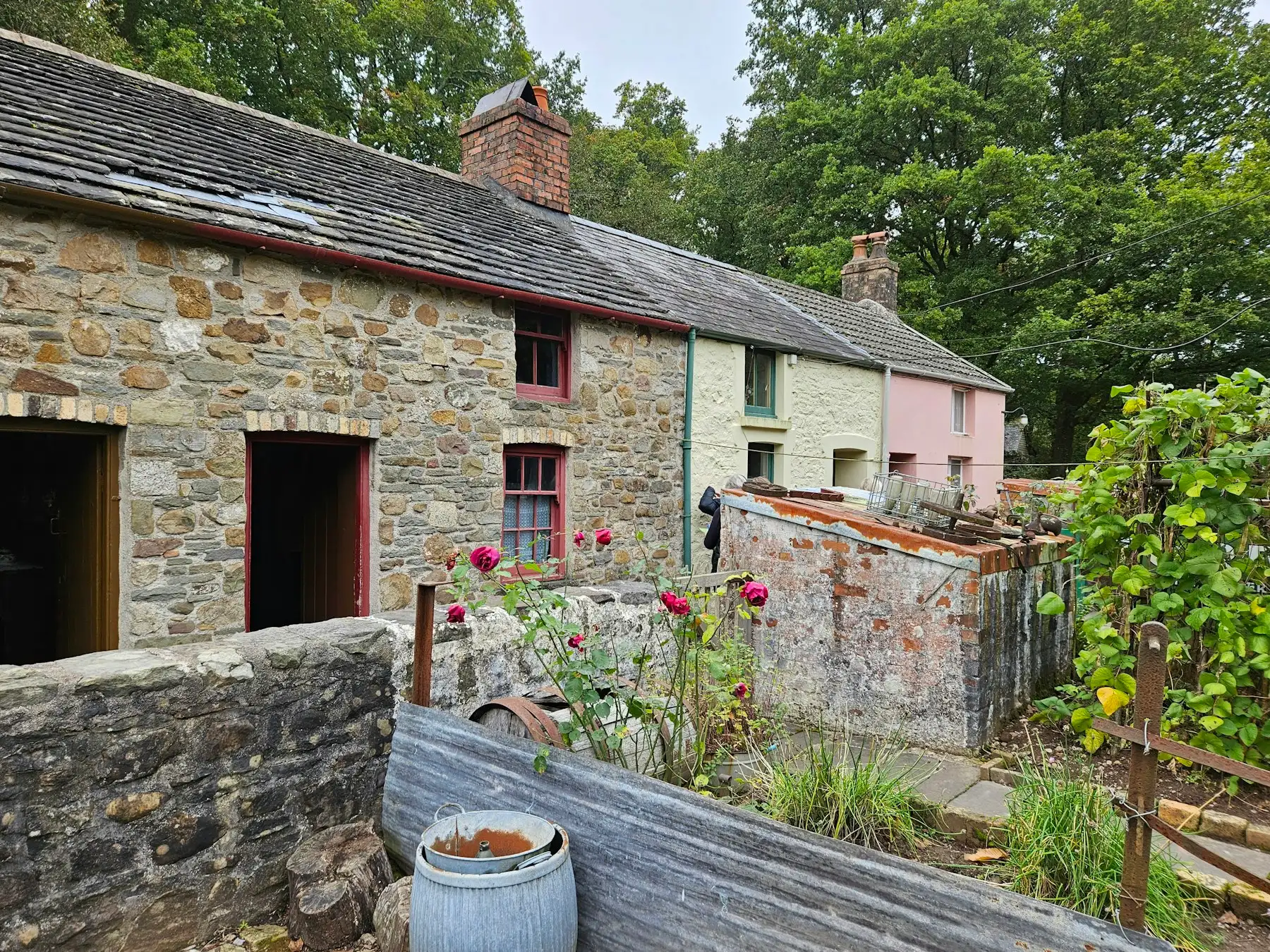 A row of stone cottages with slate roofs and a brick chimney