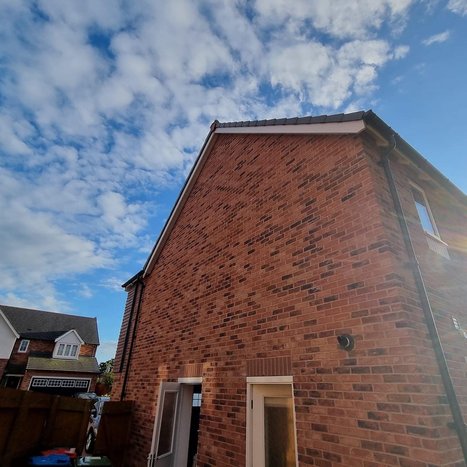 A tall red-brick gable end rising against a blue sky with scattered cloud
