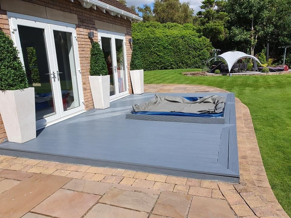A raised timber deck painted mid grey outside white French doors, with a lawn beyond
