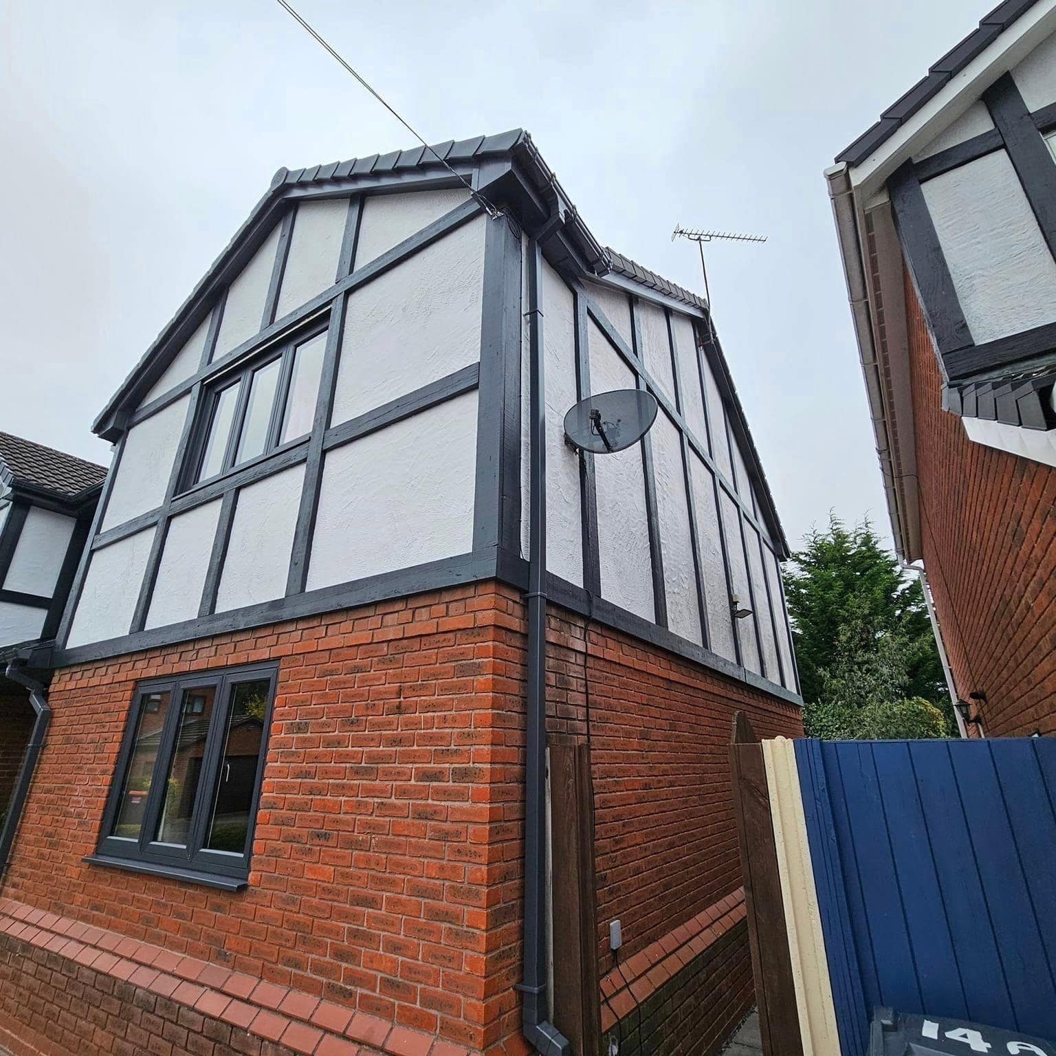 A black-and-white timbered gable end above red brick, seen from the side of the house