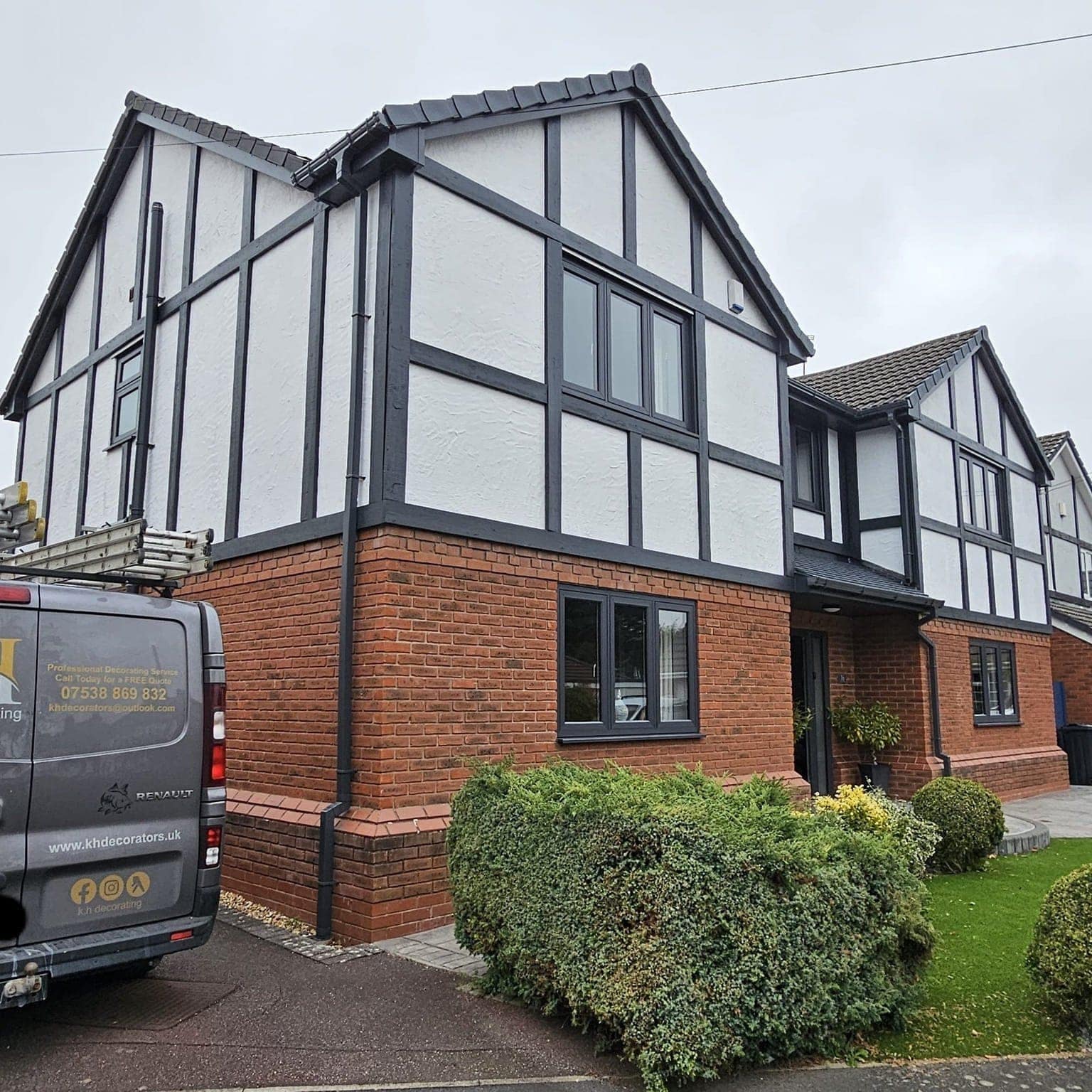 The side of the black-and-white mock-Tudor house, with a KH Painting and Decorating van parked on the drive