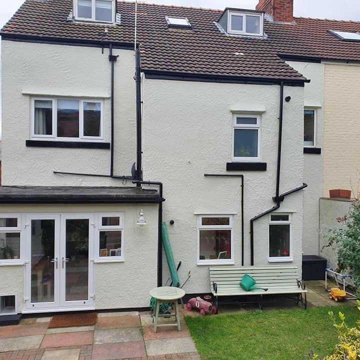 The same rear elevation finished: render coated clean white, sills in black, the masking gone
