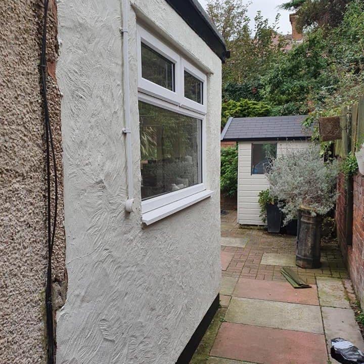 The same wall finished, the patched repairs lost under one even white textured coat