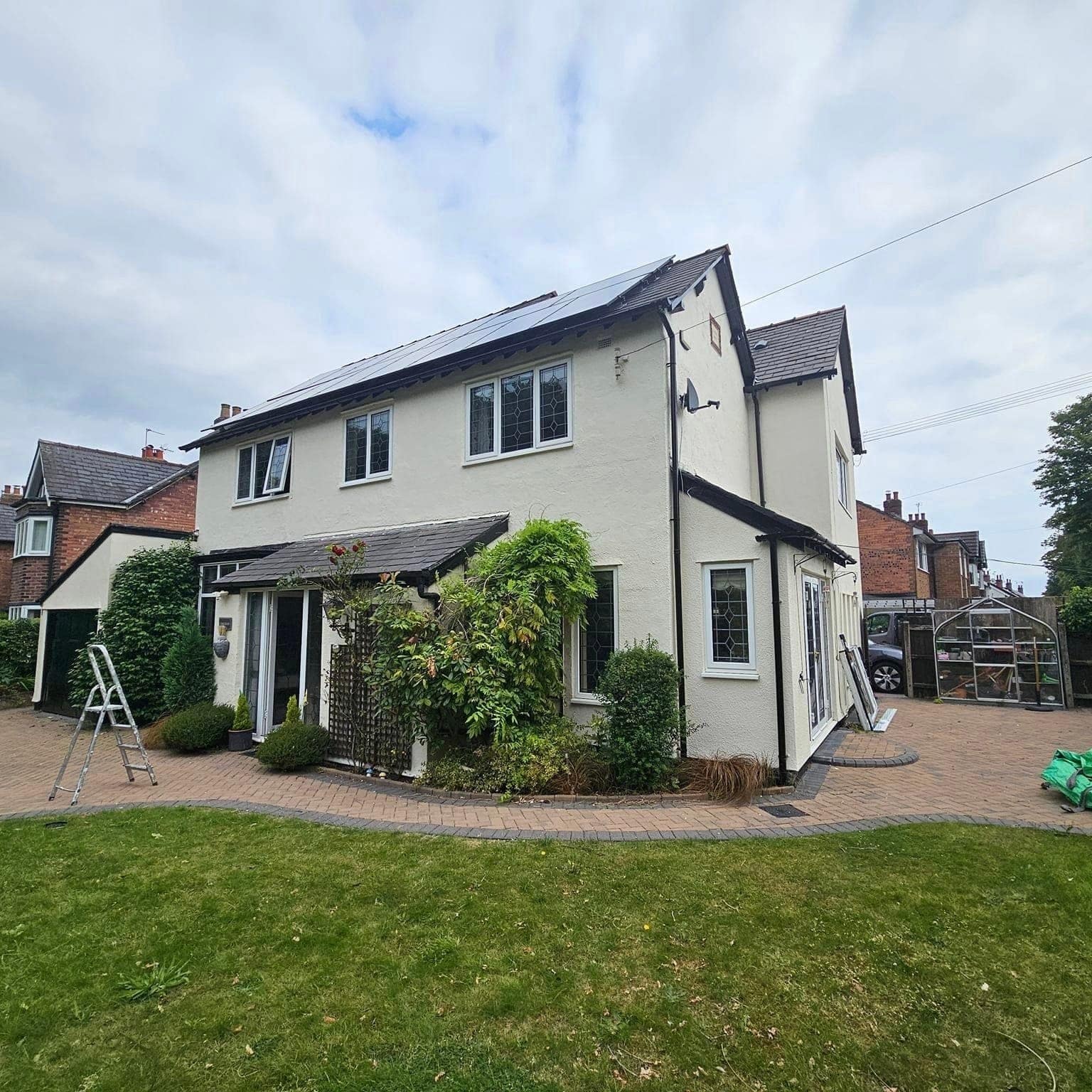The garden side of a cream-rendered detached house, with a ladder up against the wall