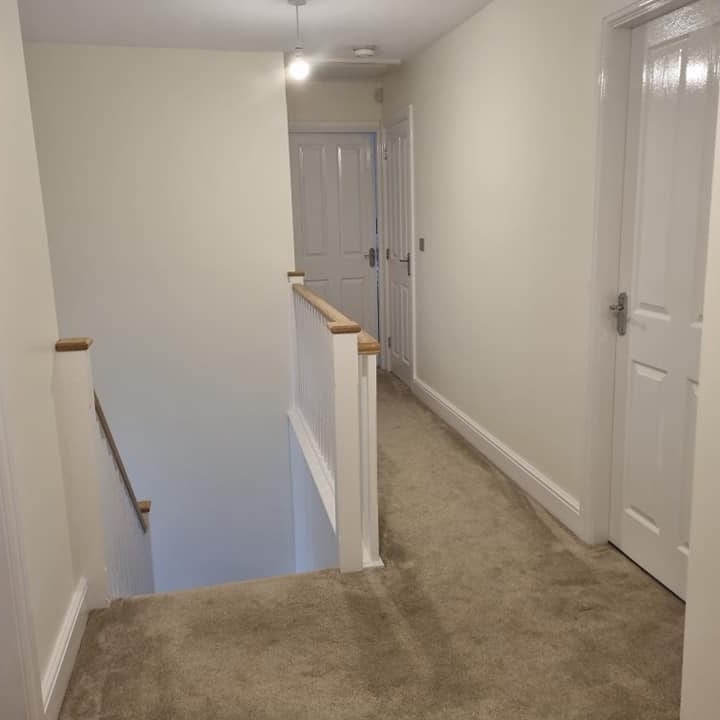 A finished landing with white doors and a white balustrade