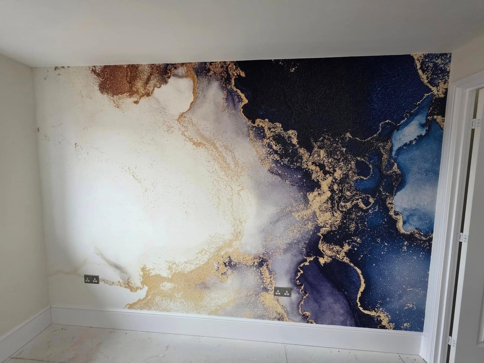 A full-wall mural of navy, white and gold marbling hung across a bedroom wall