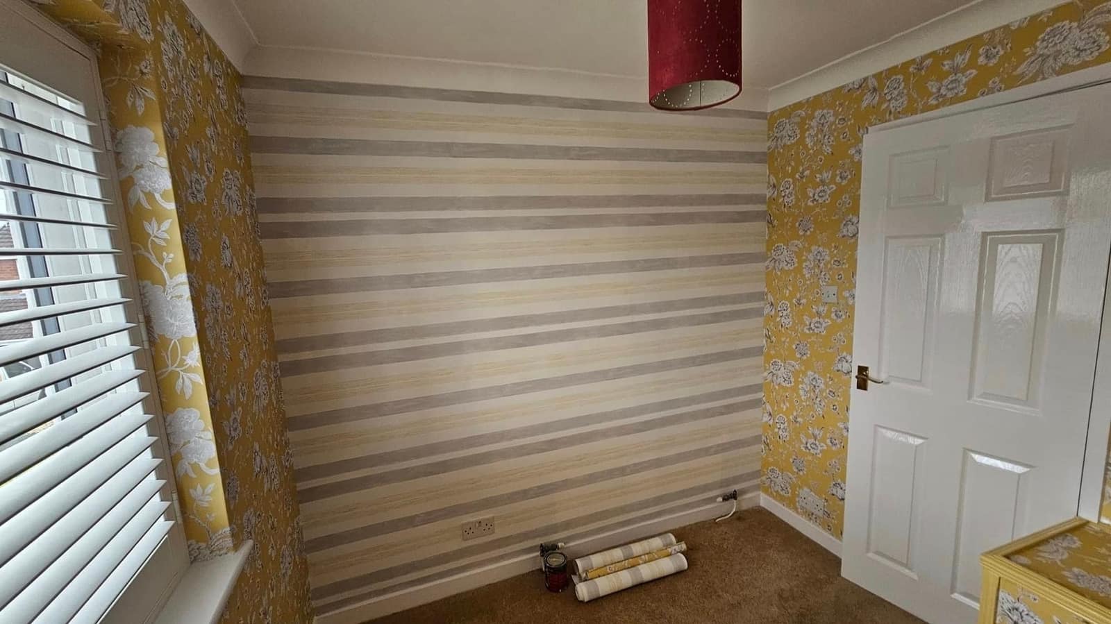 The same bedroom from the window: mustard floral paper with a striped paper on the end wall