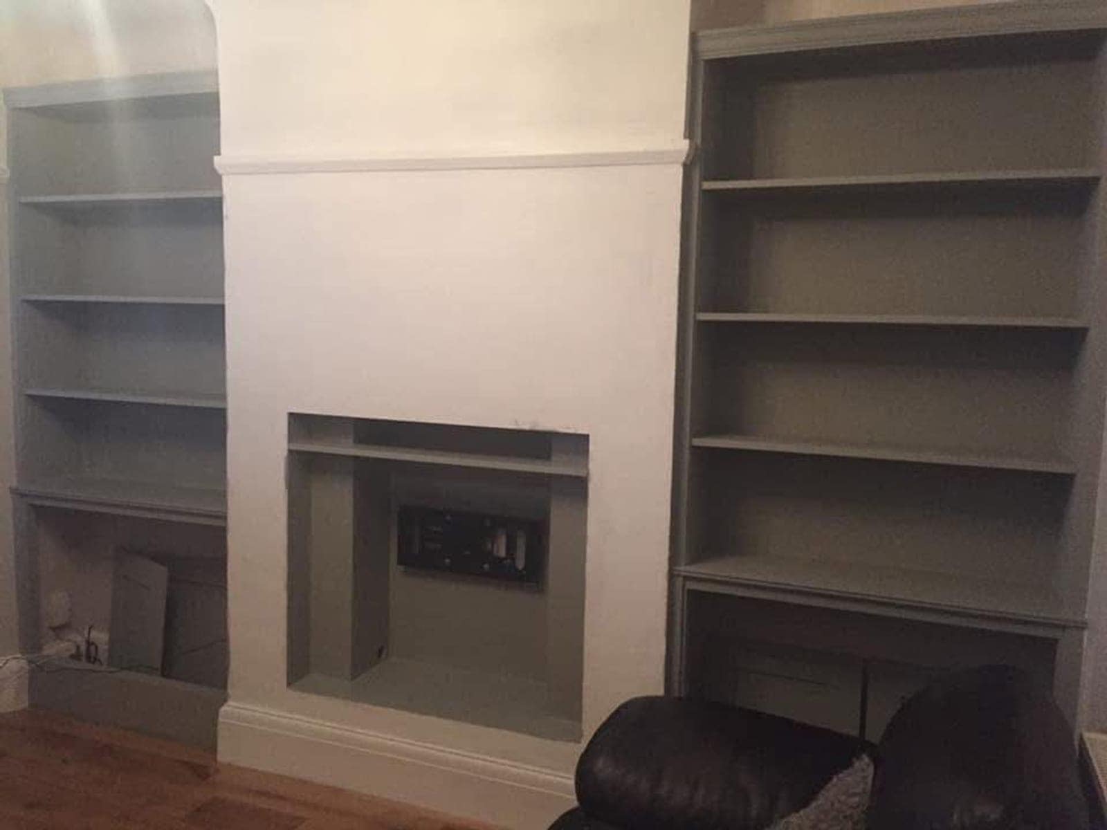 Finished alcove shelving either side of a chimney breast, painted in a soft grey-green