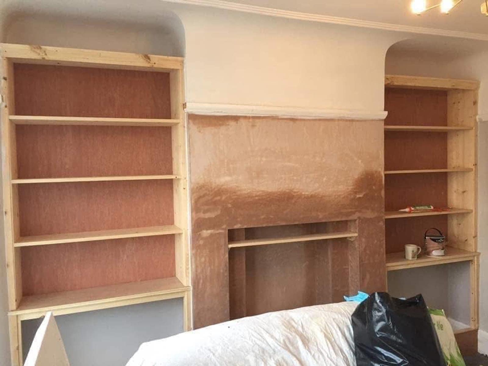 Alcove units in bare timber and ply, chimney breast in fresh plaster