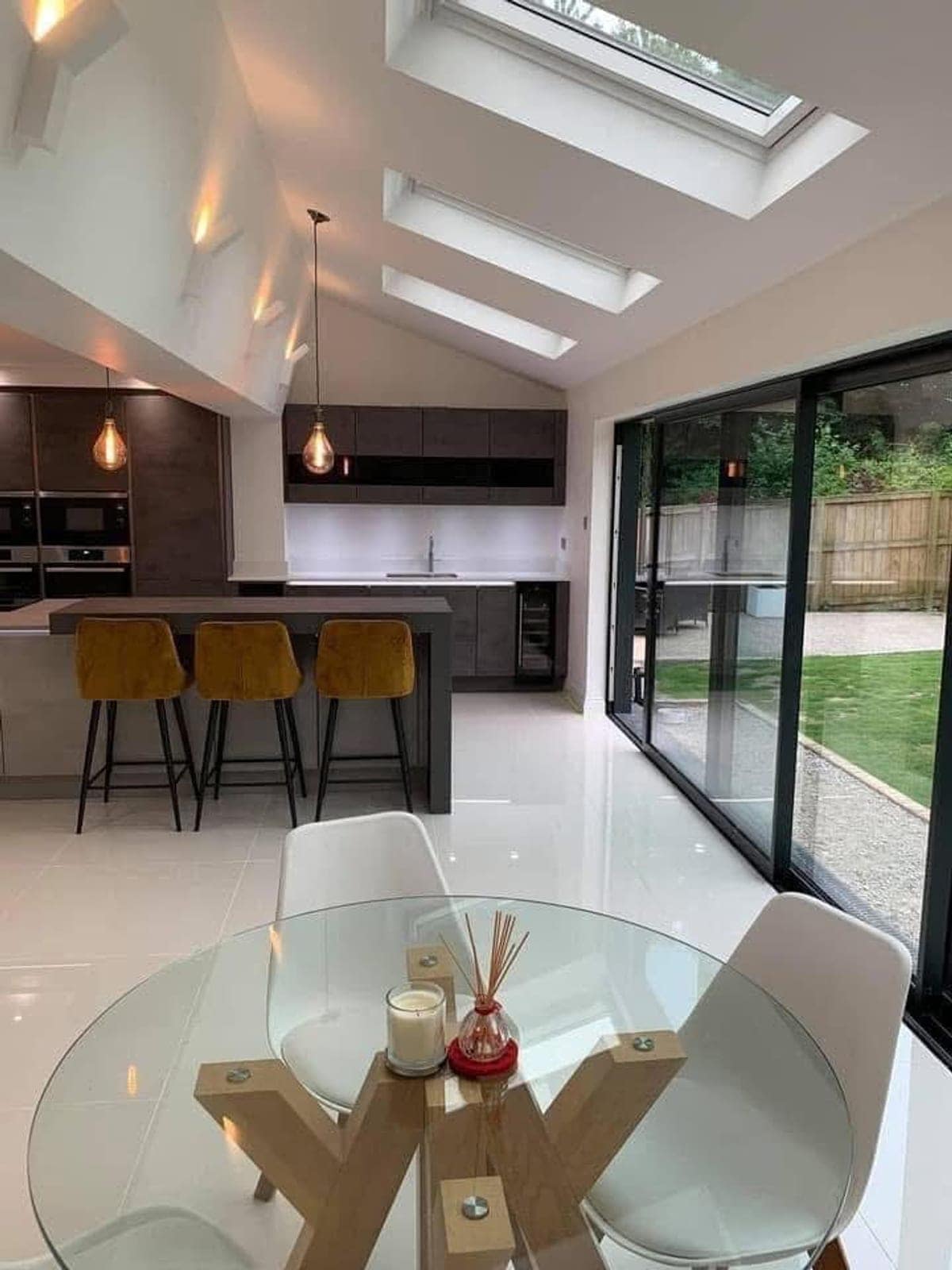 Open-plan kitchen and diner with a vaulted ceiling, roof lights and black sliding doors to the garden