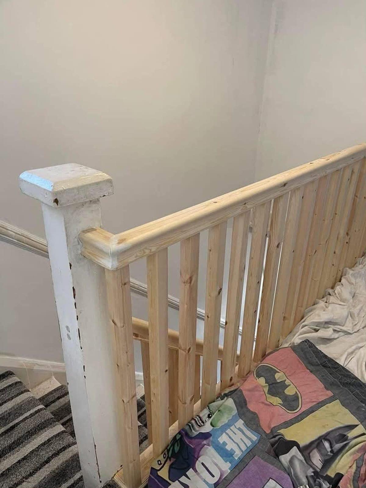 New pine spindles and handrail, unpainted, beside the old white newel